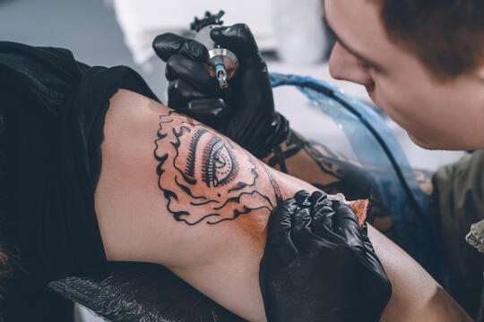 Tatovør jobber med tatovering i studio