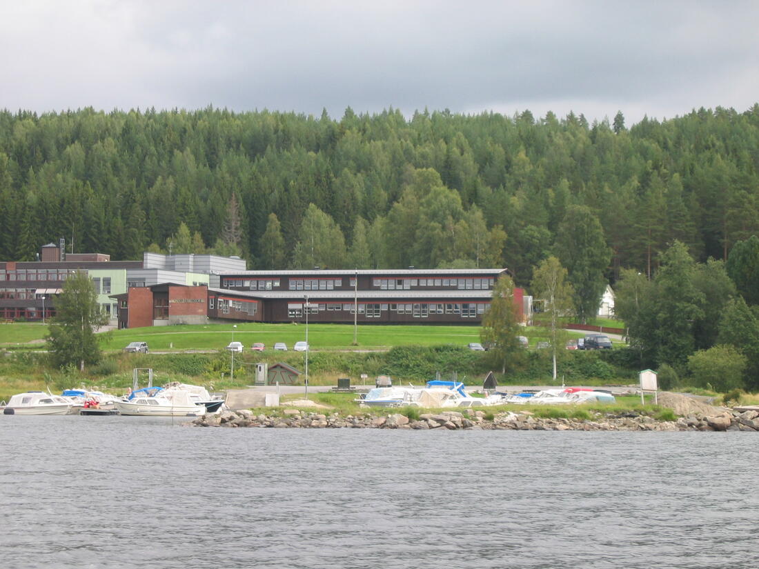 Sommerbilde av Storsjøen med båter som ligger fortøyd og Garvik skole i bakgrunnen
